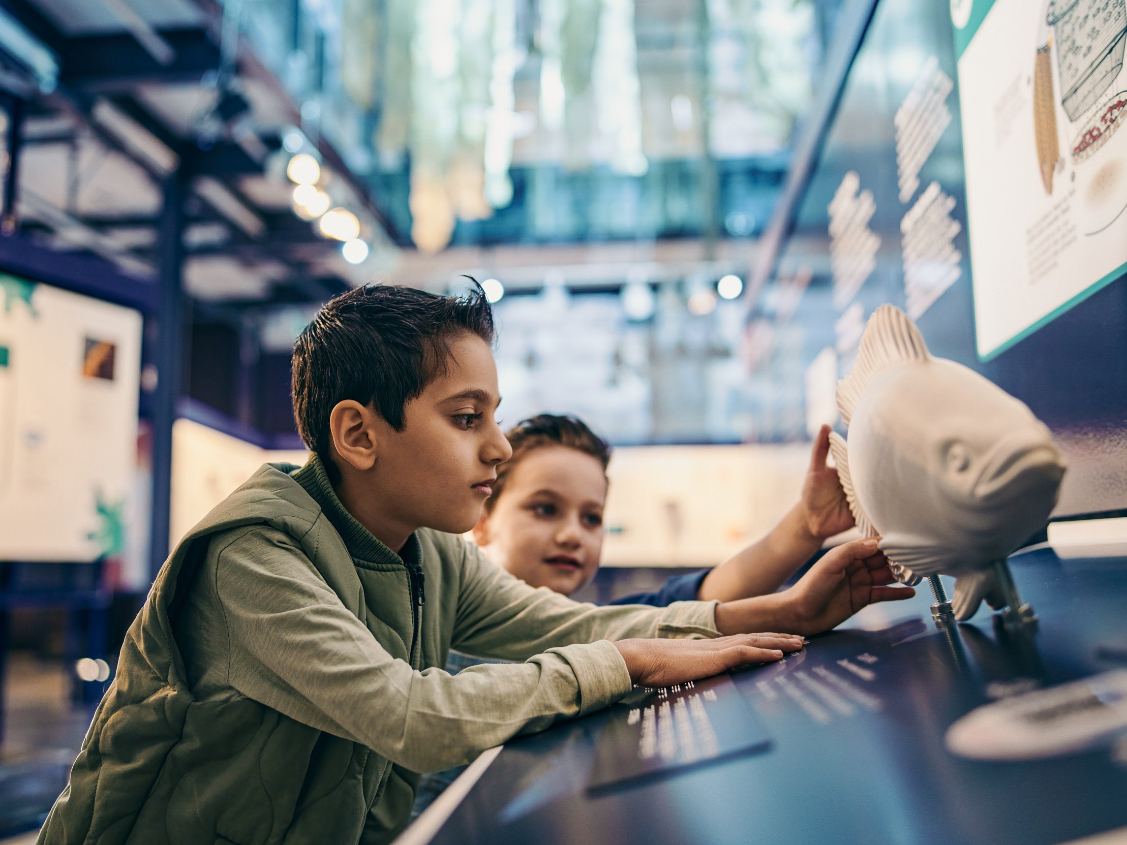 Two children touch a model of a fish in the aquaculture exhibition.