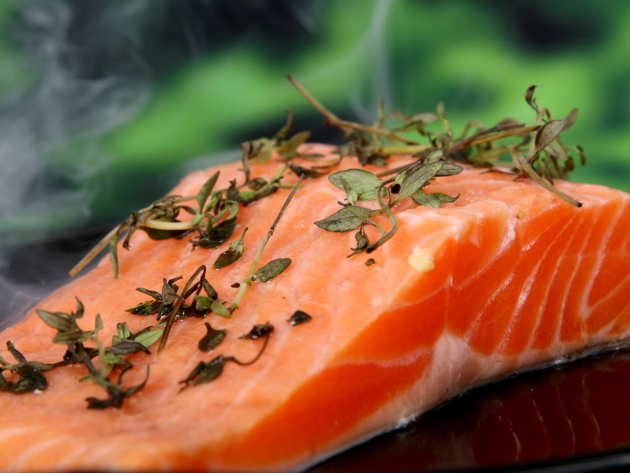 A fillet of salmon with herbs on top.