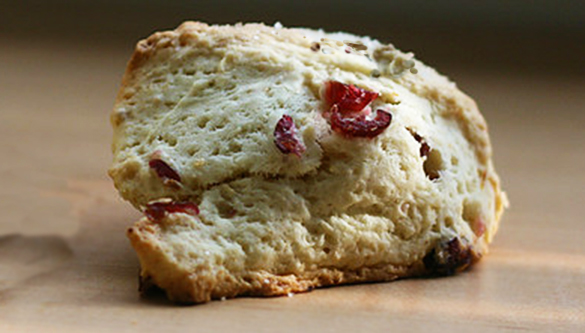 Gros plan sur un scone, tacheté de canneberges rouges.