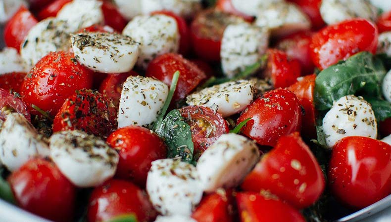 Close-up of tomato and bocconcini salad. The salad has diced cherry tomatoes, cheese, fresh herbs and dried herbs.