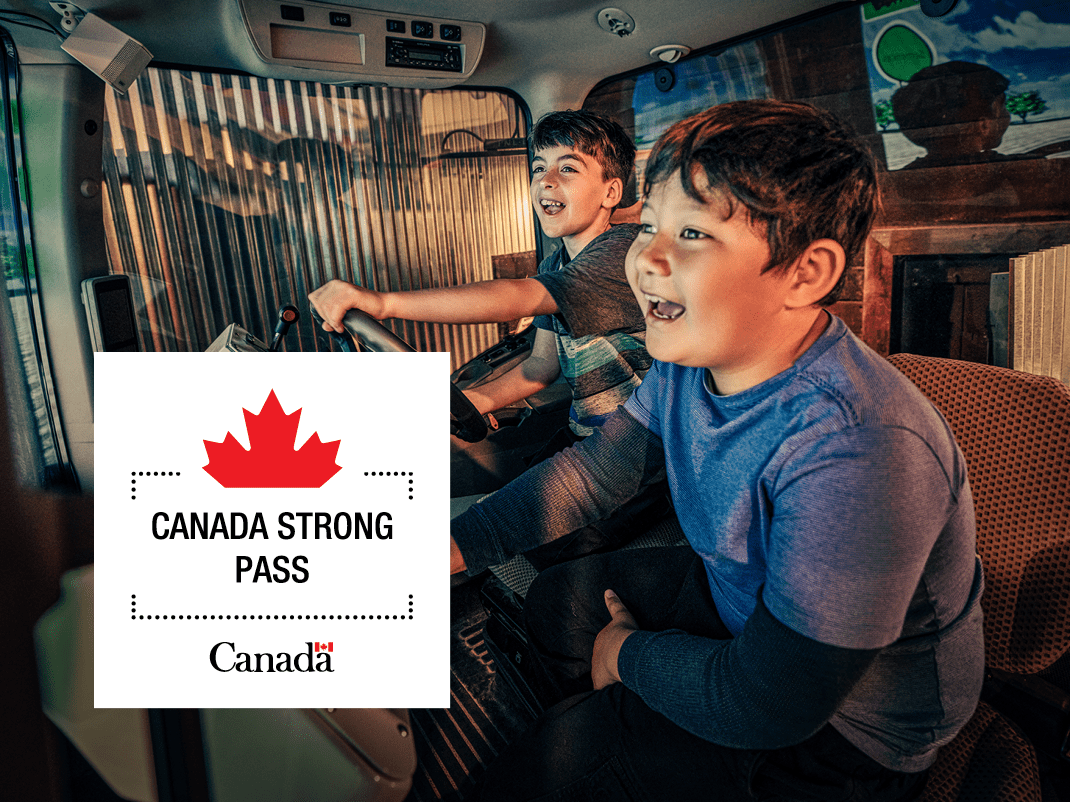 Two happy children sit in a tractor cab. A logo with a half maple leaf and the words Canada Strong Pass and Canada appear.