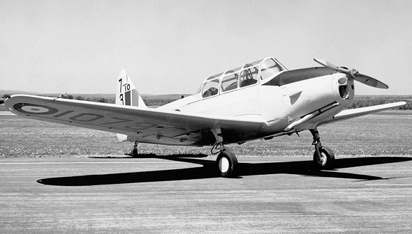 Photo en noir et blanc d'un petit avion historique, avec une hélice à l'avant. L'avion Fairchild PT-26B Cornell est sur une piste d'atterrissage.