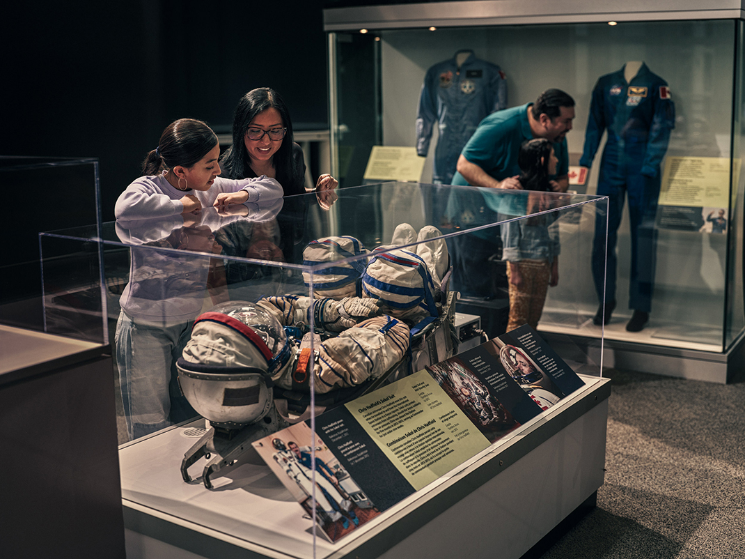 An adult and child gaze at a space suit on display at at the museum.