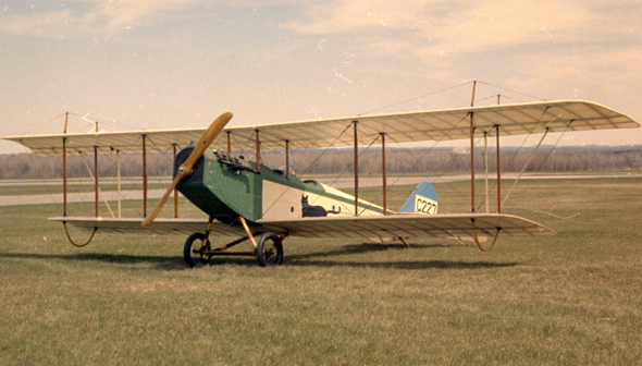 Avion Curtiss JN-4 Canuck en extérieur dans un champ herbeux.