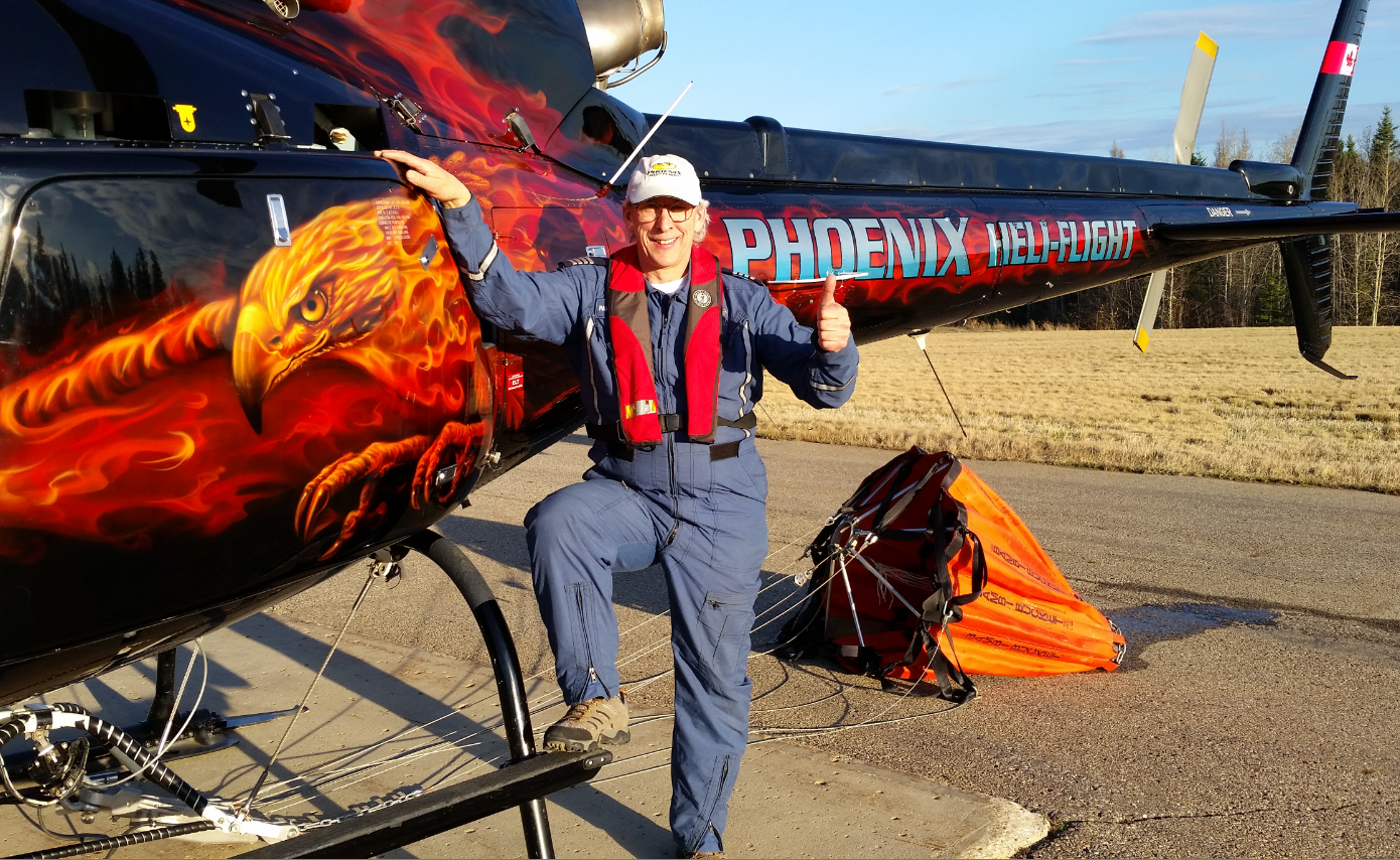 Photo d'une personne se tenant à côté d'un hélicoptère dont le flanc est orné d'un phénix enflammé.