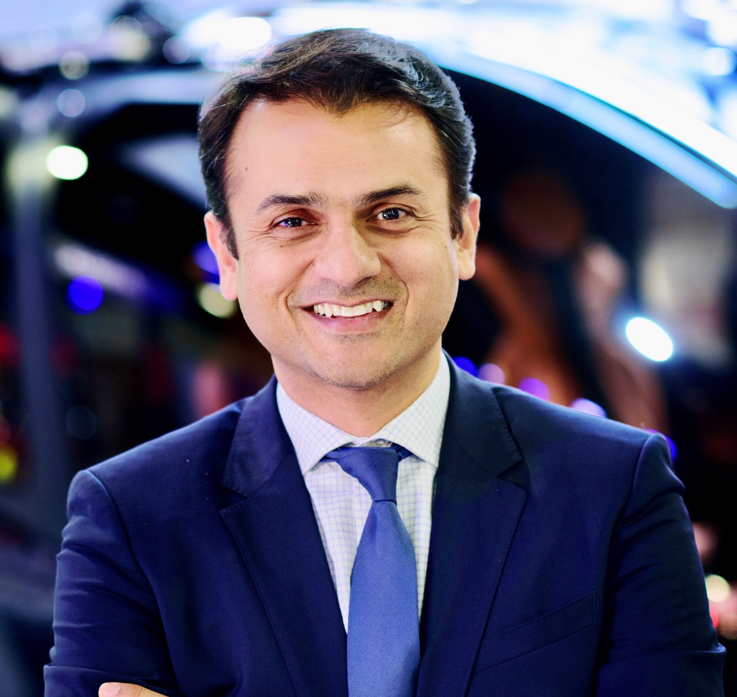 Smiling headshot of a person with short dark hair, wearing a suit