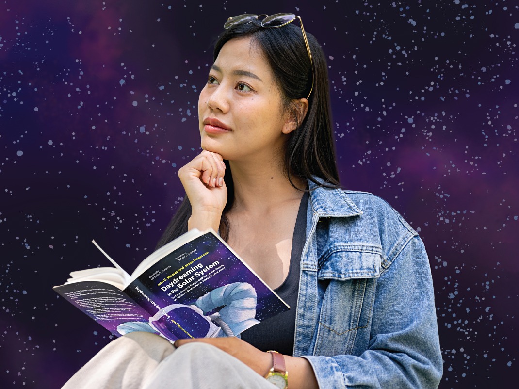 A woman wearing a denim jacket holds an open book titled Daydreaming in the Solar System. She rests her chin on her hand, gazing thoughtfully upward against a starry, purple space-themed background.