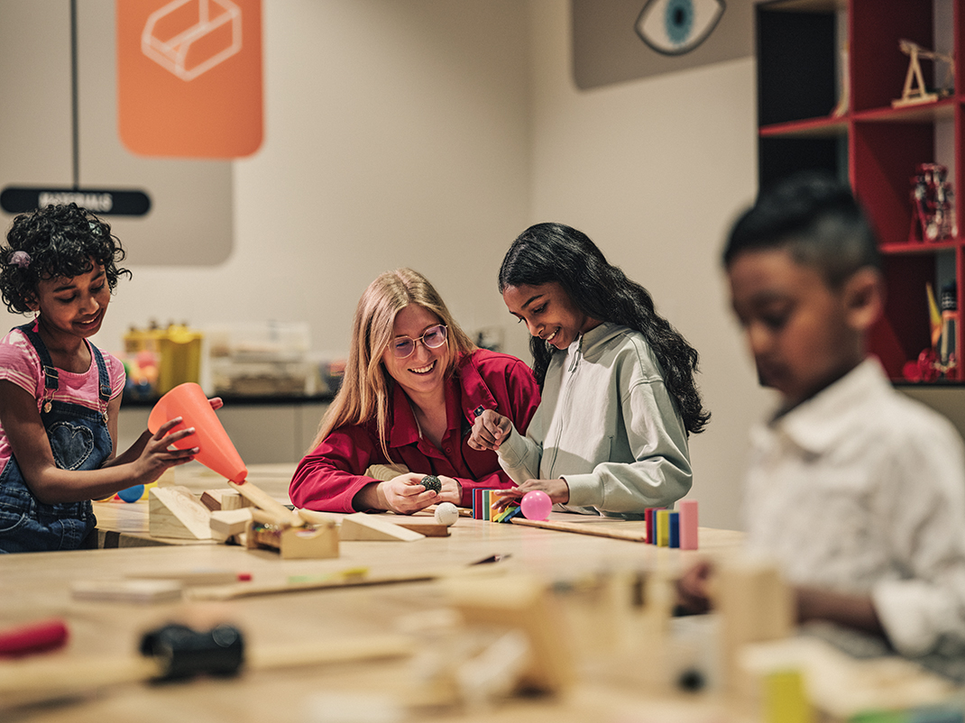 A group of students work at a table using a series of wires and materials to conduct experiments.