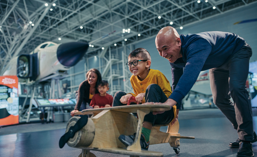 Une famille joue avec un avion en bois miniature dans le musée