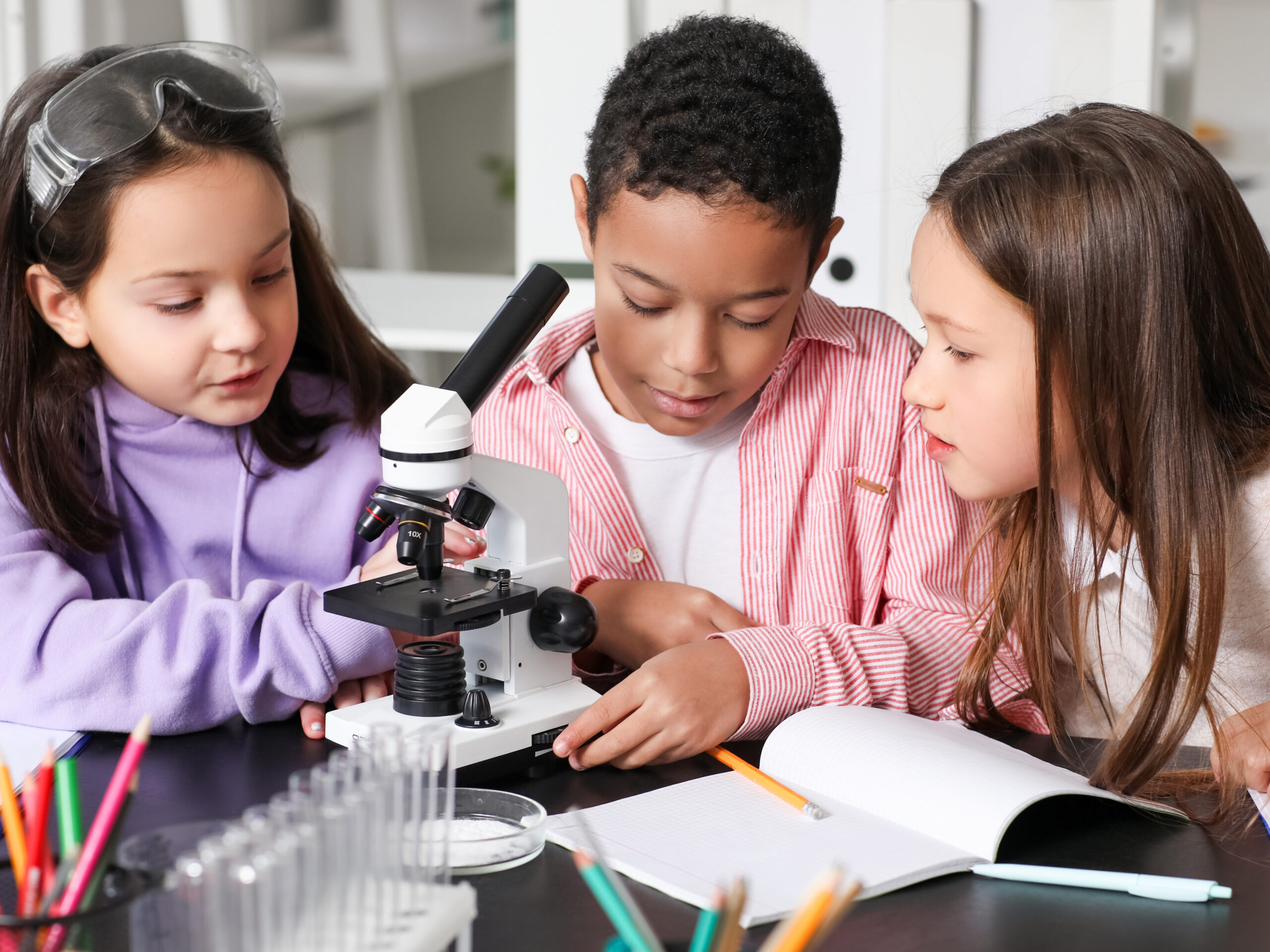 Little children with microscope studying Chemistry in science classroom