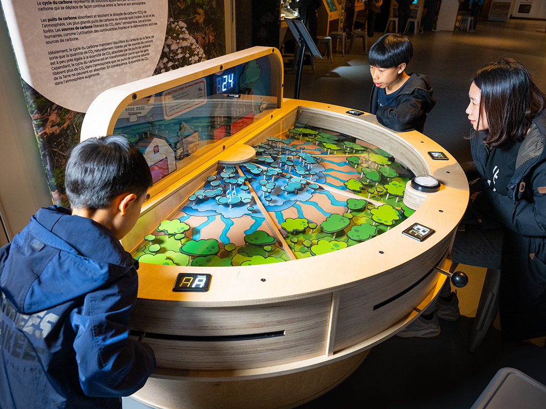 Young visitors smile and laugh while interacting with the Our Climate Quest: Small Steps to Big Change exhibition