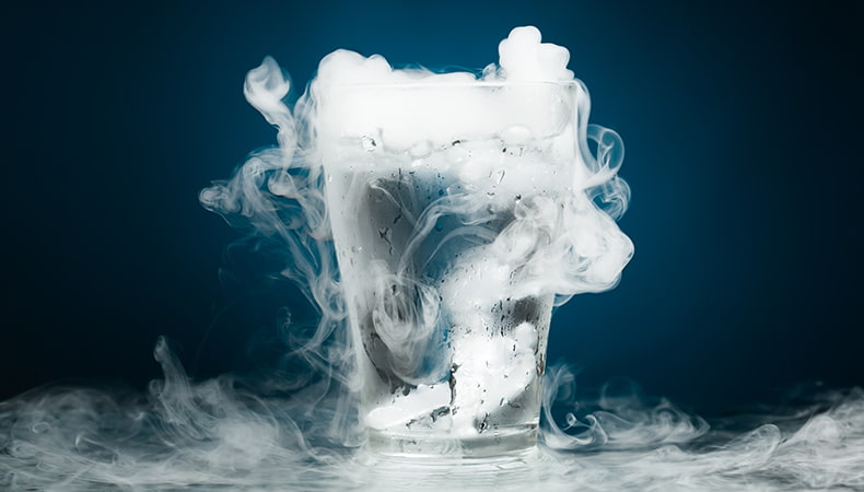 Glass of water with dry ice, creating a fog-like effect as vapor rises and surrounds the glass