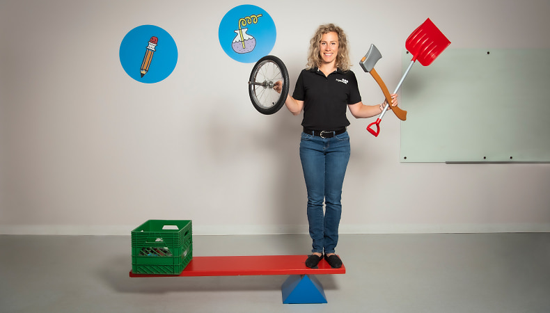 A museum employee showing the functionality of a simple machine while holding other simple machines