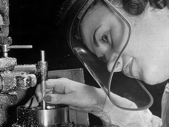 A women leans in close with a face protector during aircraft construction in 1942.